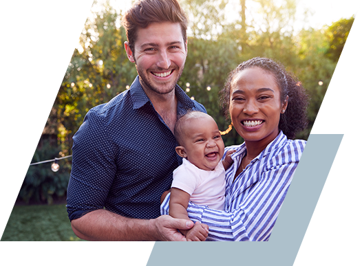 Photo of a young couple with toddler looking into the camera and smiling.